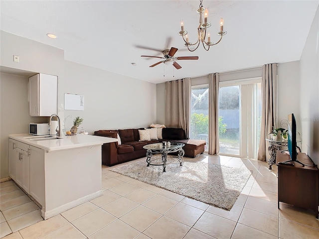 tiled living room featuring ceiling fan with notable chandelier and sink