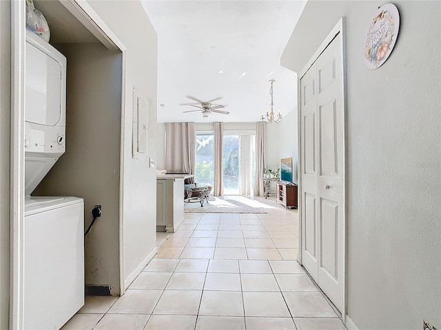 laundry room with ceiling fan with notable chandelier, stacked washer / dryer, and light tile patterned flooring