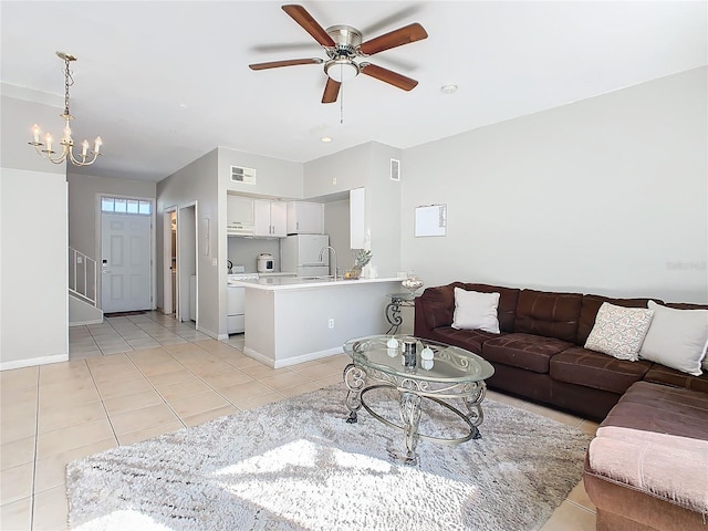 living room featuring light tile patterned floors, ceiling fan with notable chandelier, and sink