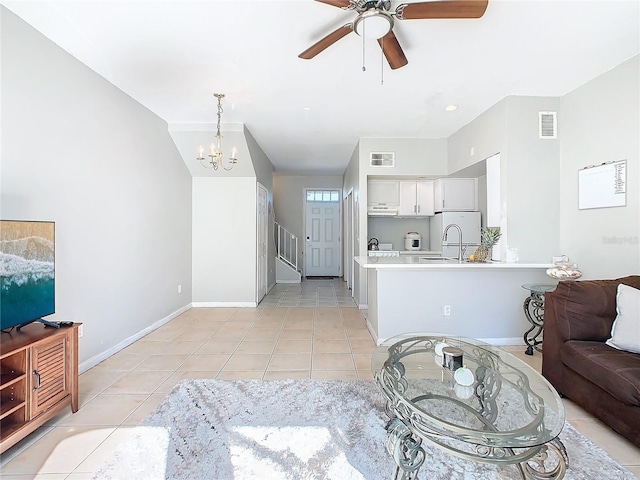 tiled living room featuring ceiling fan with notable chandelier and sink