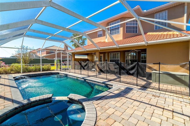 view of swimming pool featuring glass enclosure, an in ground hot tub, a patio area, and ceiling fan