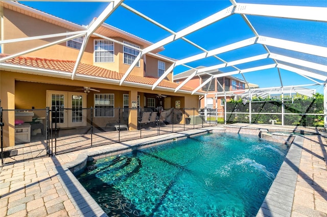 view of pool with glass enclosure, ceiling fan, a patio area, and french doors