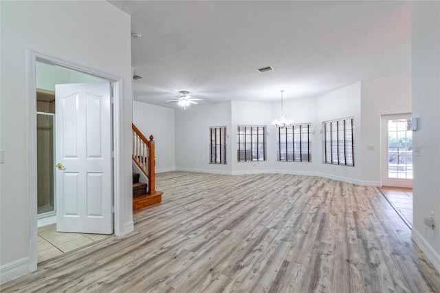 unfurnished room featuring a textured ceiling, ceiling fan with notable chandelier, and light hardwood / wood-style flooring