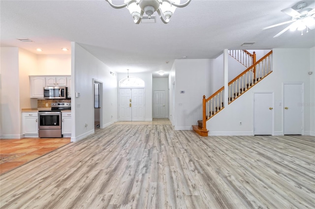 unfurnished living room with a textured ceiling, light hardwood / wood-style flooring, and ceiling fan with notable chandelier