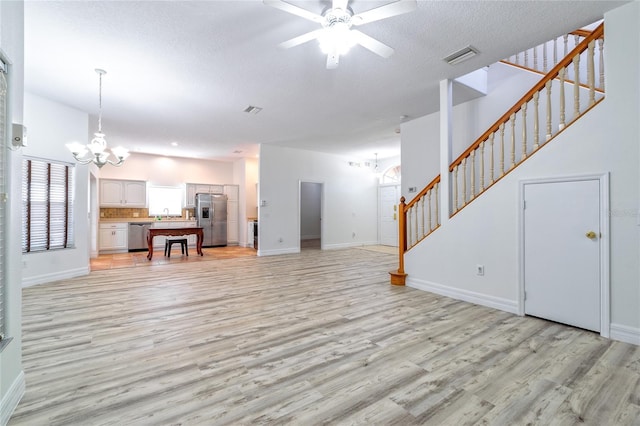 living room with a textured ceiling, ceiling fan with notable chandelier, and light hardwood / wood-style floors