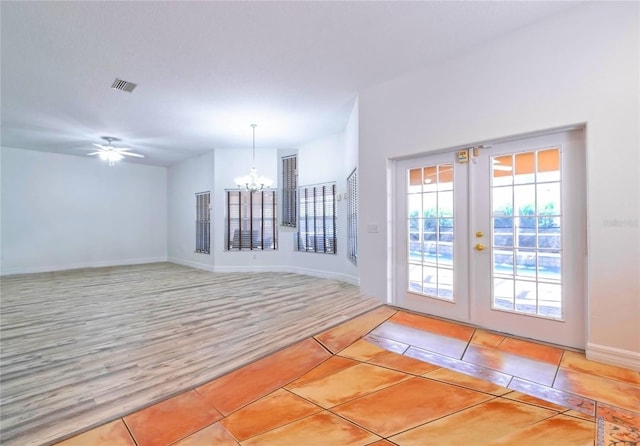 interior space featuring french doors, light tile patterned floors, and ceiling fan with notable chandelier