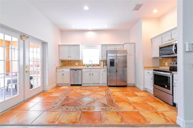 kitchen featuring a healthy amount of sunlight, white cabinetry, stainless steel appliances, and tasteful backsplash