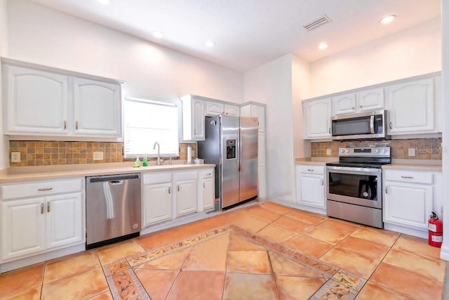 kitchen featuring decorative backsplash, stainless steel appliances, sink, white cabinetry, and light tile patterned flooring