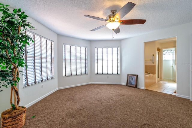 carpeted empty room featuring ceiling fan and a textured ceiling