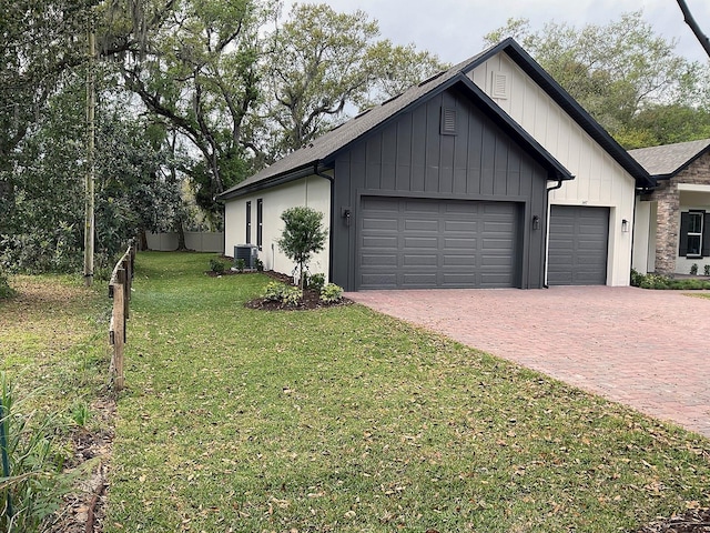 view of front of property with board and batten siding, a front lawn, cooling unit, decorative driveway, and an attached garage