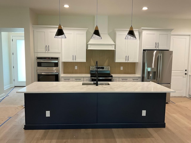 kitchen with light wood-style flooring, appliances with stainless steel finishes, an island with sink, and white cabinets