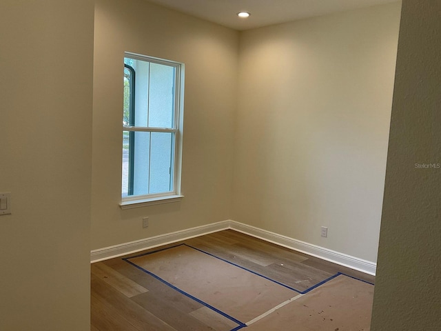 empty room with plenty of natural light, baseboards, and dark wood-style flooring