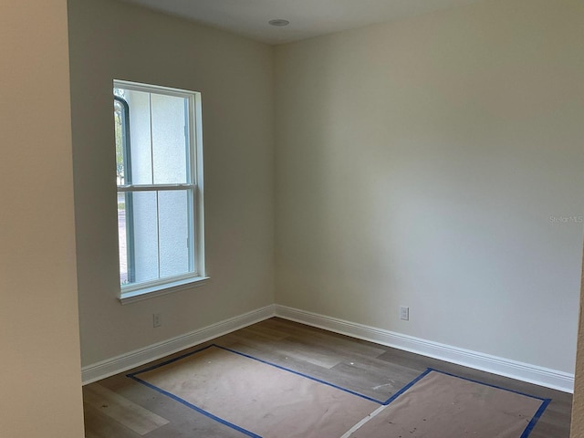 unfurnished room with baseboards and dark wood-style flooring