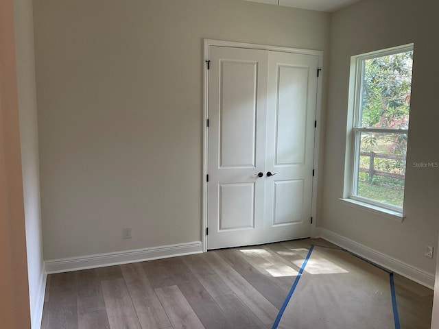 unfurnished bedroom with wood finished floors, a closet, and baseboards