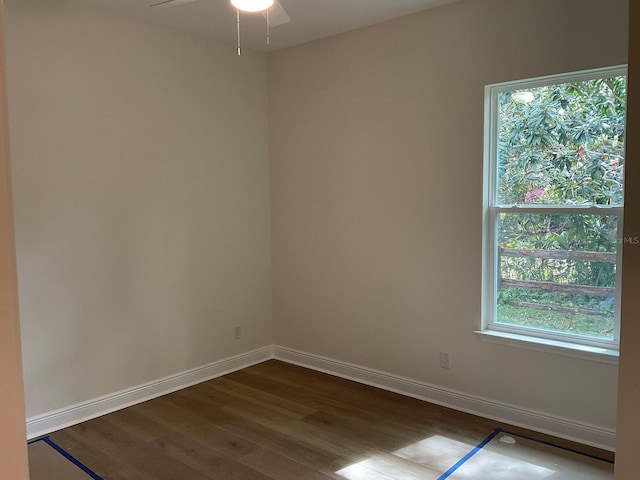 spare room featuring a ceiling fan, dark wood-type flooring, and baseboards