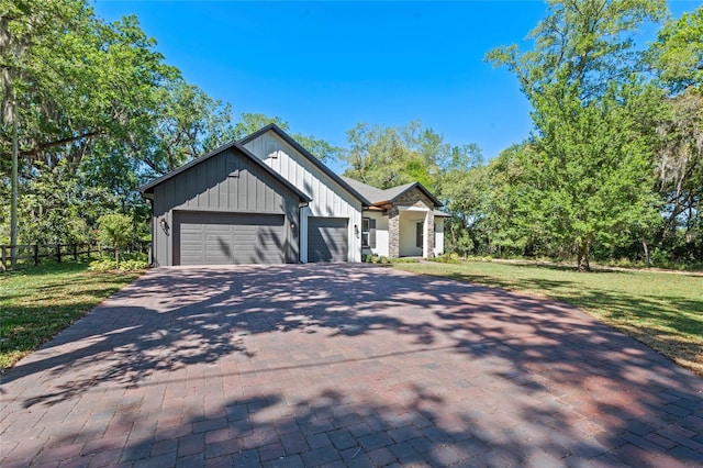 view of front of house with board and batten siding, decorative driveway, a front lawn, a garage, and fence