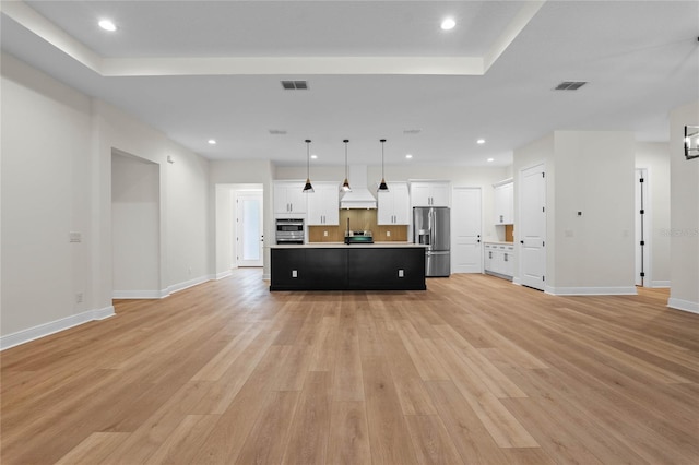 kitchen featuring custom exhaust hood, open floor plan, light wood-type flooring, and appliances with stainless steel finishes