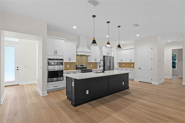 kitchen featuring white cabinetry, visible vents, custom exhaust hood, appliances with stainless steel finishes, and a sink
