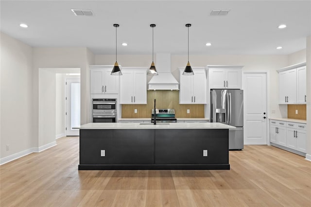 kitchen with tasteful backsplash, premium range hood, visible vents, stainless steel appliances, and a sink
