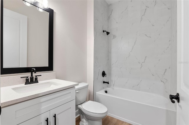 full bath featuring toilet, wood finished floors, vanity, and washtub / shower combination