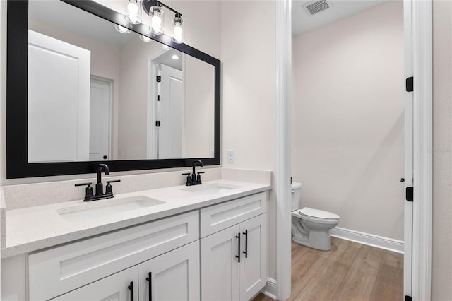 bathroom with visible vents, a sink, toilet, and wood finished floors