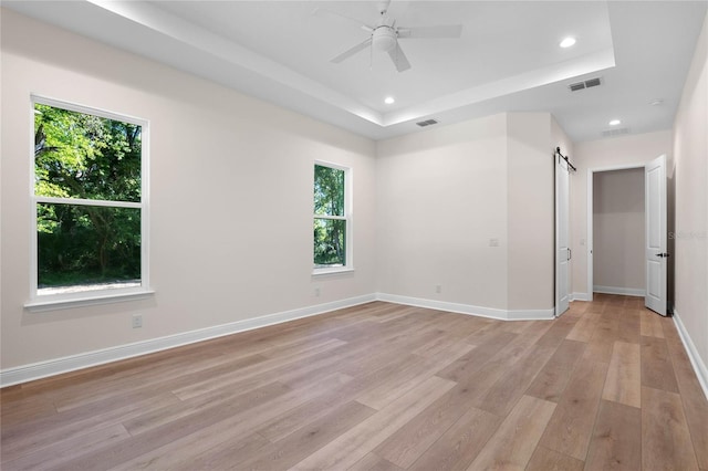 empty room with visible vents, a raised ceiling, ceiling fan, recessed lighting, and light wood finished floors