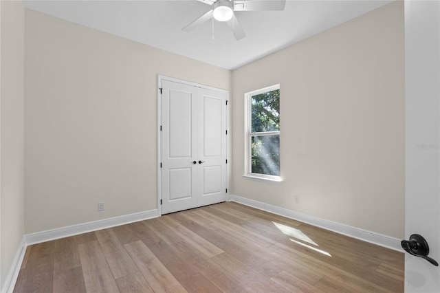 unfurnished bedroom featuring a closet, baseboards, a ceiling fan, and wood finished floors