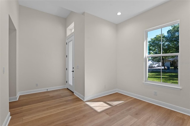 empty room with baseboards, light wood-style floors, and a healthy amount of sunlight