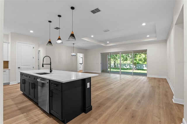 kitchen featuring visible vents, a sink, dark cabinetry, and a raised ceiling