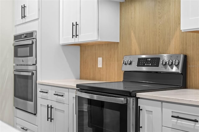 kitchen with white cabinetry, appliances with stainless steel finishes, and light stone countertops