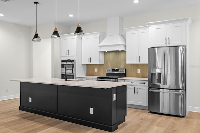 kitchen featuring an island with sink, tasteful backsplash, custom range hood, stainless steel appliances, and light wood finished floors