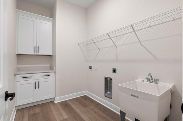 clothes washing area featuring hookup for an electric dryer, baseboards, washer hookup, a sink, and wood finished floors