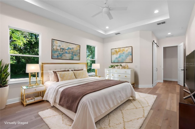 bedroom with light wood-style floors, recessed lighting, visible vents, and a tray ceiling