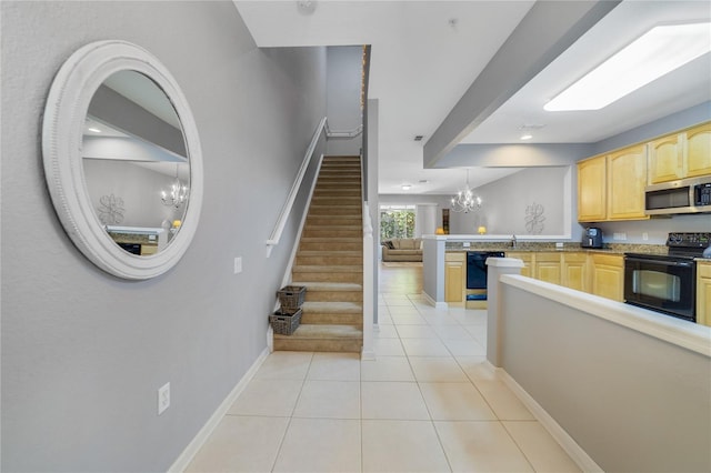 kitchen featuring kitchen peninsula, decorative light fixtures, light brown cabinetry, light tile patterned floors, and black appliances