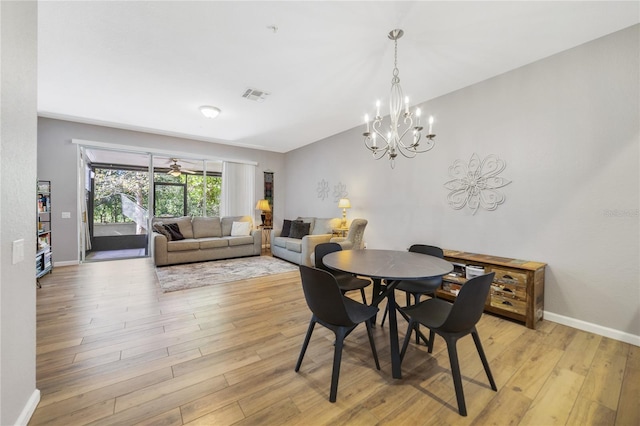 dining room with ceiling fan with notable chandelier and light wood-type flooring