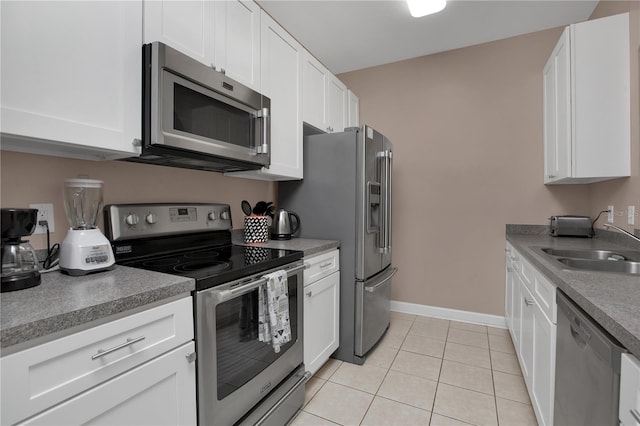 kitchen featuring white cabinetry, sink, light tile patterned floors, and stainless steel appliances