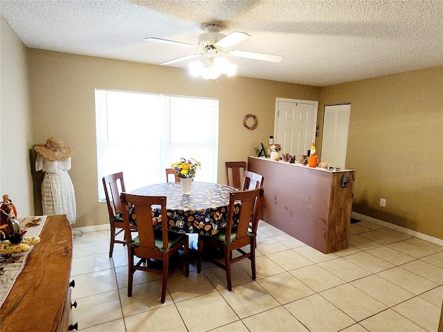 tiled dining area with ceiling fan and a textured ceiling