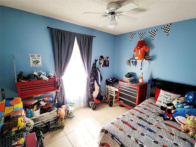 bedroom with ceiling fan, light tile patterned flooring, and a textured ceiling