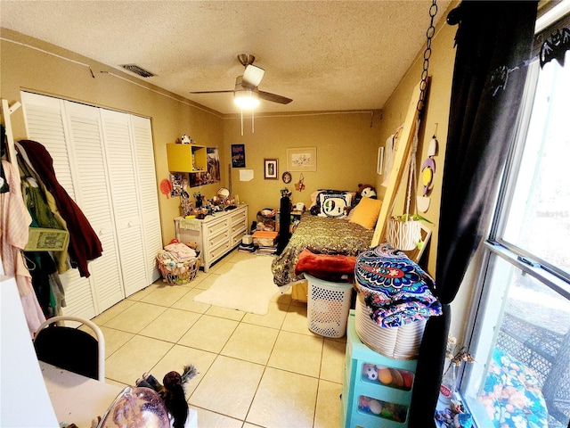 tiled bedroom with a textured ceiling, ceiling fan, multiple windows, and a closet