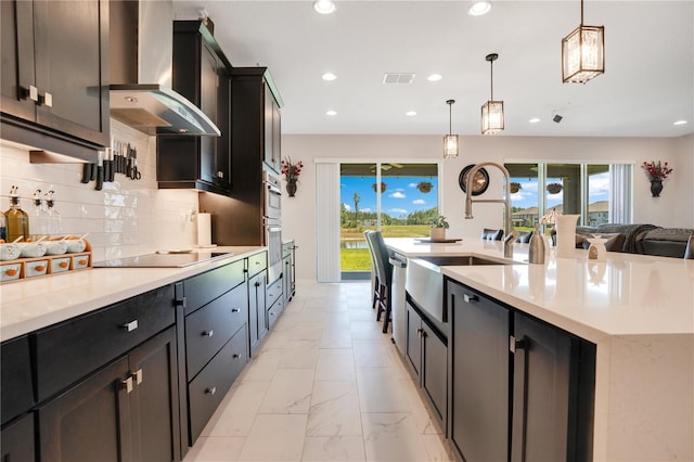 kitchen with wall chimney exhaust hood, a spacious island, decorative light fixtures, black electric cooktop, and decorative backsplash