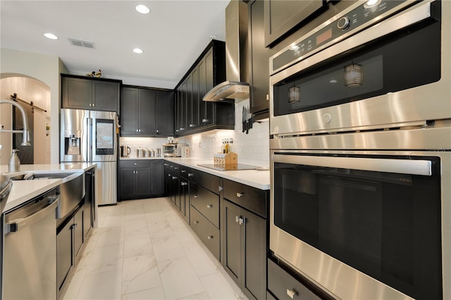 kitchen featuring wall chimney exhaust hood, decorative backsplash, and stainless steel appliances