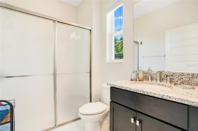 bathroom featuring vanity, toilet, and a shower with door