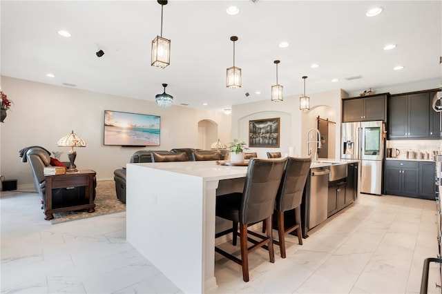 kitchen featuring a large island with sink, decorative backsplash, decorative light fixtures, a kitchen bar, and stainless steel appliances