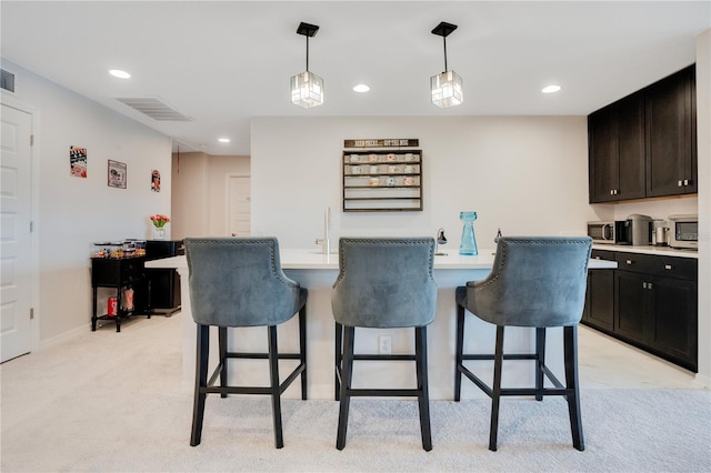 bar featuring light carpet, dark brown cabinets, and decorative light fixtures