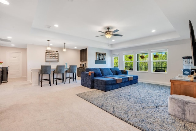 carpeted living room featuring a tray ceiling and ceiling fan