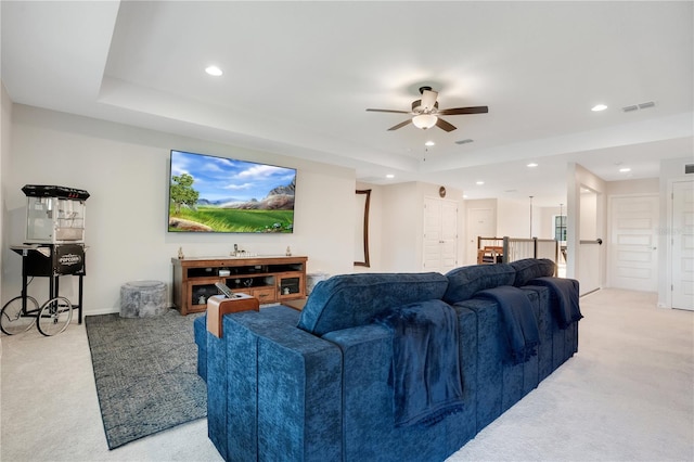 carpeted living room with a tray ceiling and ceiling fan