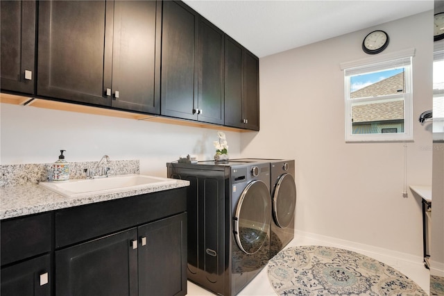 clothes washing area featuring washer and clothes dryer, cabinets, and sink