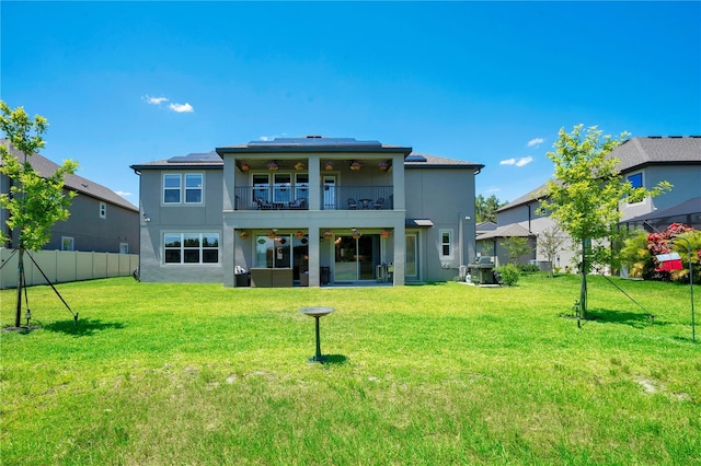 rear view of house with a yard, a balcony, and ceiling fan