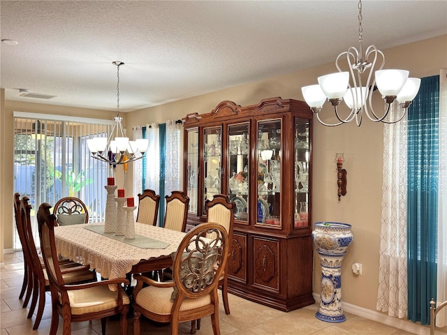 dining space with a notable chandelier, light tile patterned flooring, and a textured ceiling