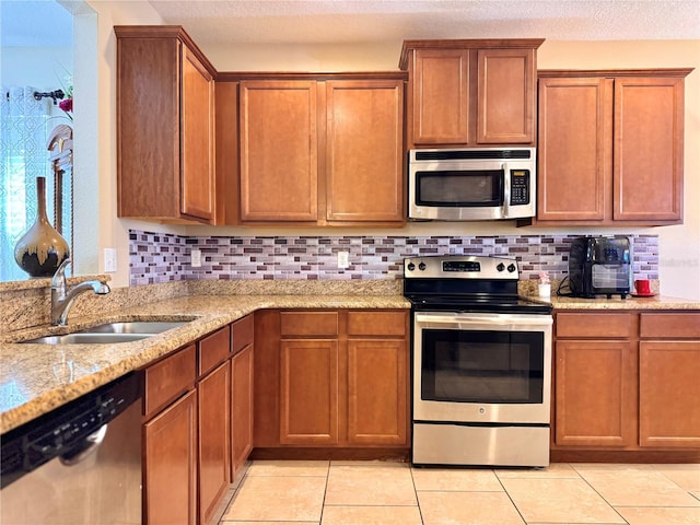 kitchen with light stone counters, sink, stainless steel appliances, and tasteful backsplash